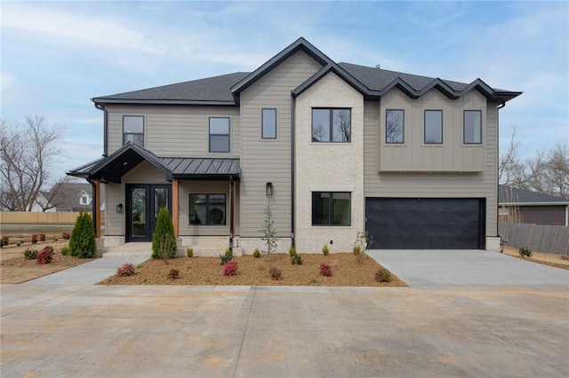 view of front of house with driveway, a standing seam roof, fence, board and batten siding, and an attached garage