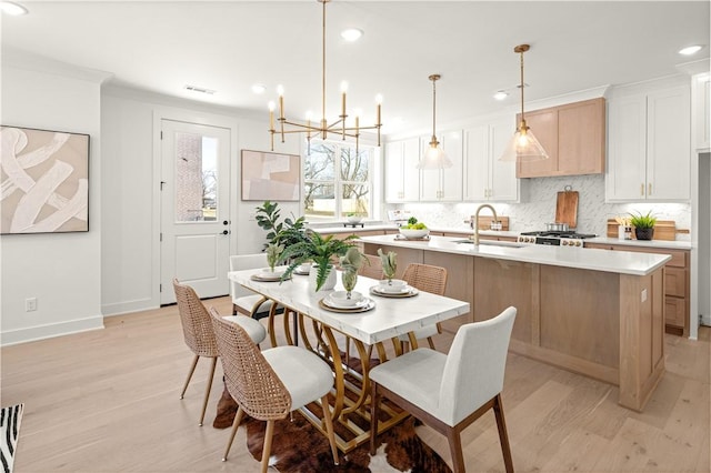 kitchen with a kitchen island with sink, tasteful backsplash, light countertops, and a sink