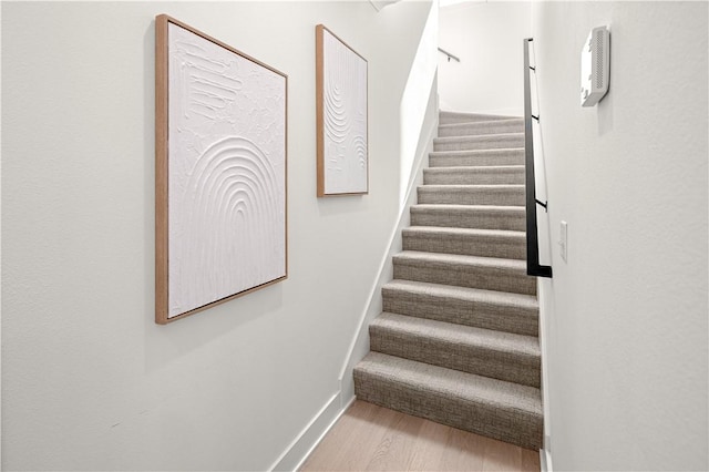 staircase featuring baseboards and wood finished floors
