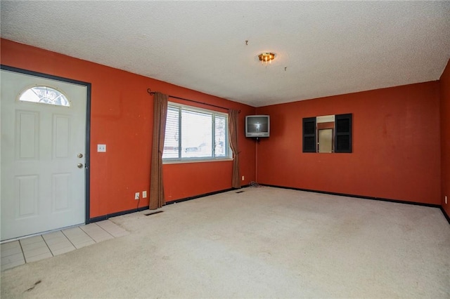 carpeted foyer entrance with tile patterned floors and a textured ceiling