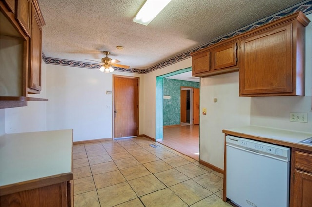 kitchen with light tile patterned flooring, ceiling fan, a textured ceiling, dishwasher, and brown cabinets