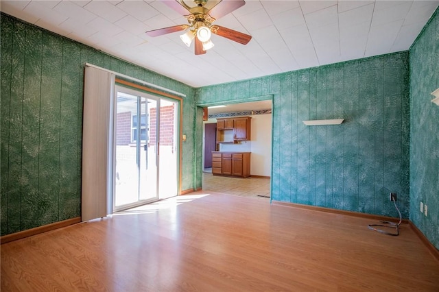 empty room featuring baseboards, light wood-type flooring, and a ceiling fan