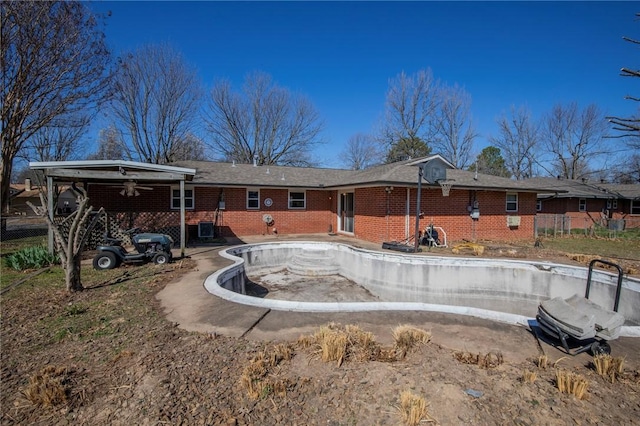 rear view of house with brick siding, a ceiling fan, and fence