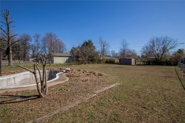 view of yard featuring an outbuilding, a storage unit, and fence