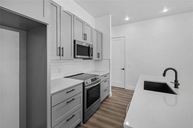 10 Reading Ln, Bella Vista, AR 72714 - kitchen featuring dark wood finished floors, light countertops, decorative backsplash, appliances with stainless steel finishes, and a sink