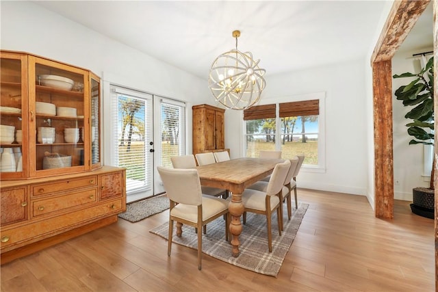 dining room featuring baseboards, plenty of natural light, a notable chandelier, and light wood-style flooring
