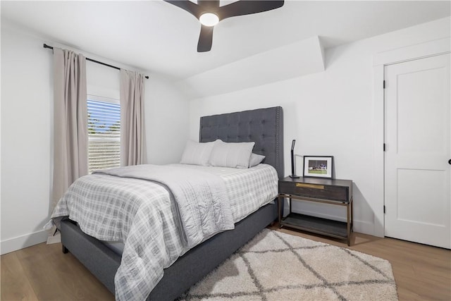 bedroom featuring baseboards, lofted ceiling, wood finished floors, and a ceiling fan
