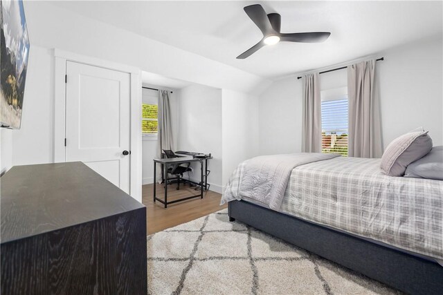 bedroom with ceiling fan, baseboards, wood finished floors, and vaulted ceiling