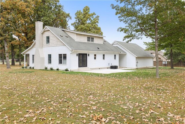 rear view of house with roof with shingles, central AC unit, a lawn, a chimney, and a patio