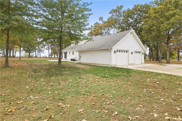 view of home's exterior with central AC unit, a lawn, a garage, and driveway