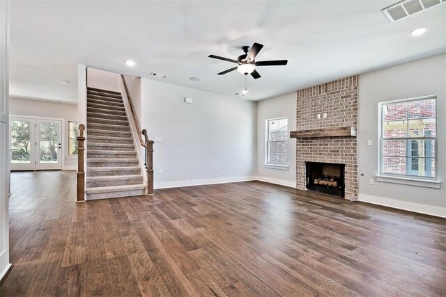 unfurnished living room with visible vents, a ceiling fan, wood finished floors, and stairway