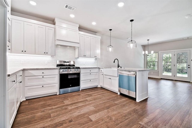 kitchen featuring visible vents, tasteful backsplash, dishwasher, gas stove, and a peninsula