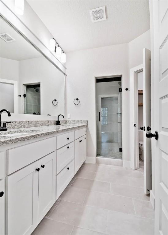 bathroom with a sink, tile patterned flooring, a stall shower, and visible vents