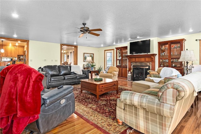 2428 Winn Mountain Loop, Mountainburg, AR 72946 - living area featuring a ceiling fan, wood finished floors, a textured ceiling, and a premium fireplace