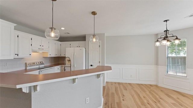108 Birch St, Centerton, AR 72719 - kitchen featuring white appliances, under cabinet range hood, light wood-type flooring, a peninsula, and a kitchen bar
