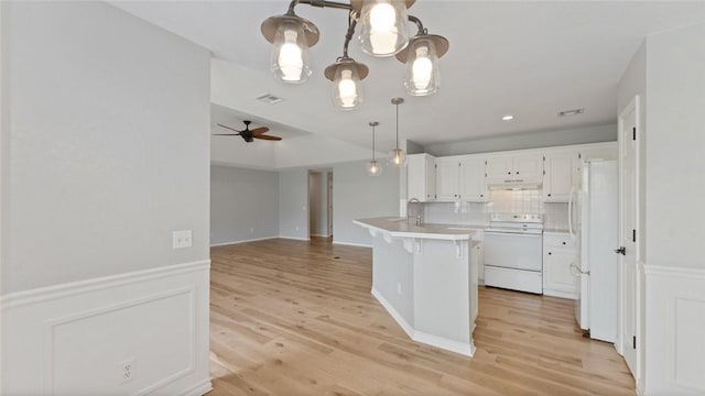 108 Birch St, Centerton, AR 72719 - kitchen featuring white appliances, under cabinet range hood, a peninsula, white cabinetry, and a kitchen breakfast bar
