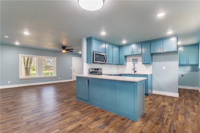 kitchen featuring stainless steel appliances, blue cabinets, decorative backsplash, baseboards, and recessed lighting