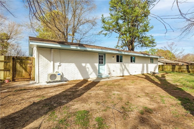 back of property featuring ac unit, brick siding, and fence