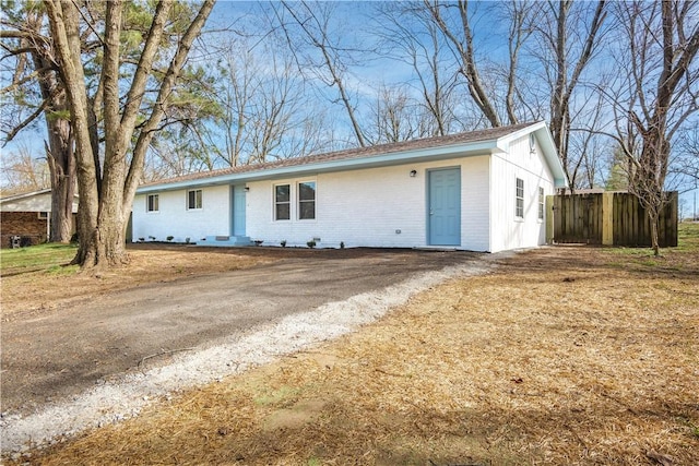 ranch-style house featuring fence, brick siding, and driveway