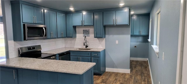 kitchen featuring stainless steel appliances, a sink, a peninsula, and decorative backsplash