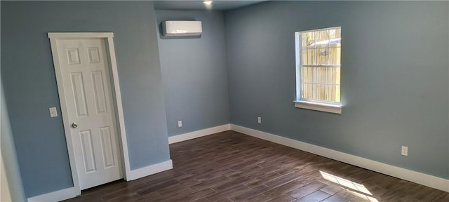 spare room with baseboards, dark wood-type flooring, and a wall unit AC