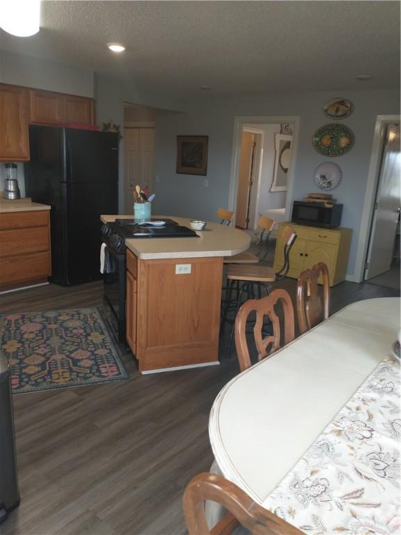 82 County Road 327, Berryville, AR 72616 - kitchen featuring black appliances, dark wood-type flooring, light countertops, brown cabinetry, and a center island