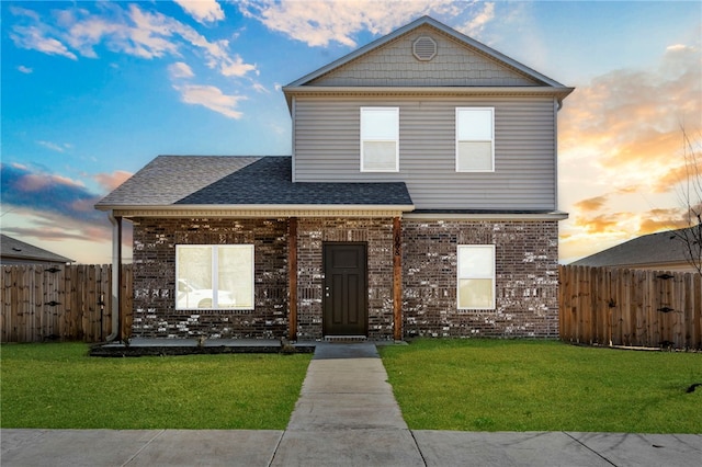traditional home with brick siding, a front yard, and fence
