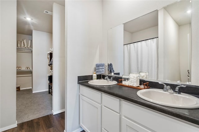 bathroom with wood finished floors, a sink, visible vents, and double vanity