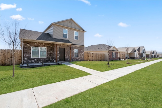 view of front facade featuring fence, brick siding, and a front yard