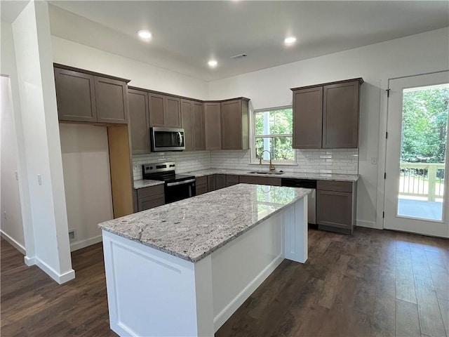 11 Romine Ln, Bella Vista, AR 72715 - kitchen featuring appliances with stainless steel finishes, dark wood finished floors, a center island, light stone countertops, and backsplash