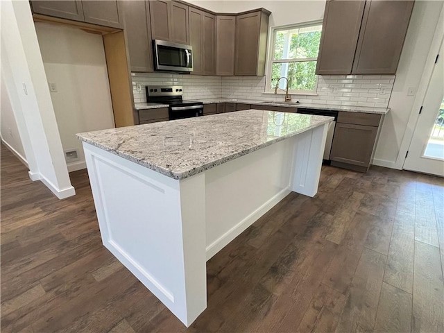 11 Romine Ln, Bella Vista, AR 72715 - kitchen with stainless steel appliances, dark wood-style floors, a kitchen island, light stone counters, and backsplash