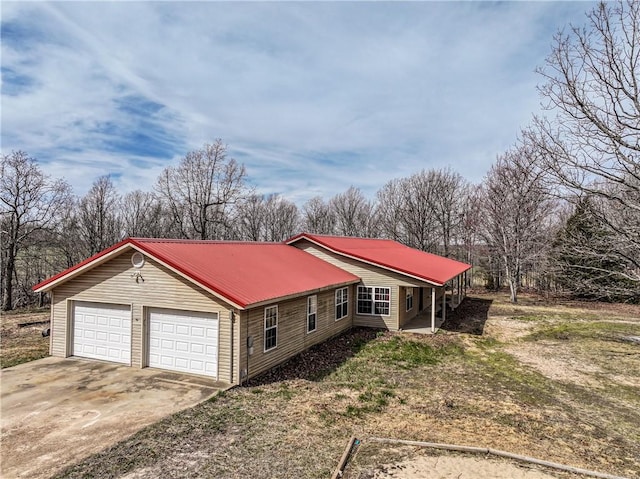 view of front of house featuring driveway, metal roof, and a garage