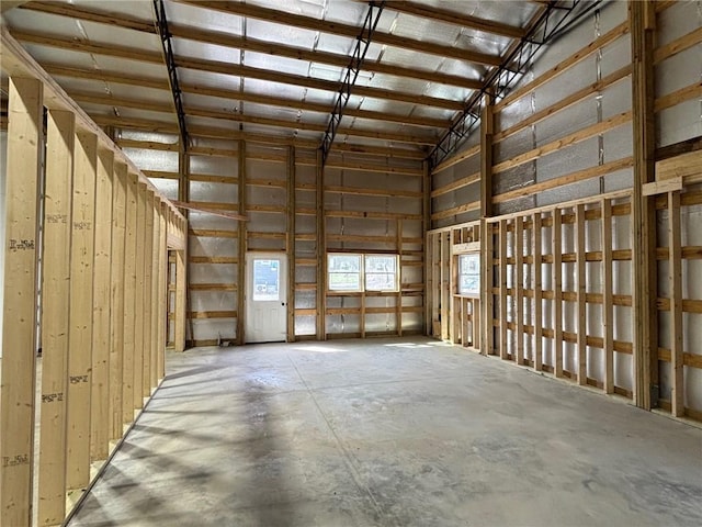 miscellaneous room with high vaulted ceiling, concrete flooring, and a garage