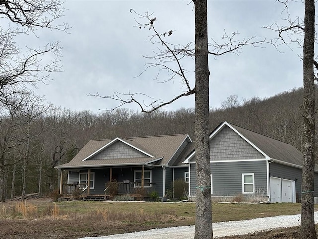 view of front of home featuring a garage, a forest view, and a porch