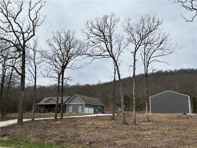 exterior space featuring an outdoor structure, an outbuilding, a wooded view, and a garage