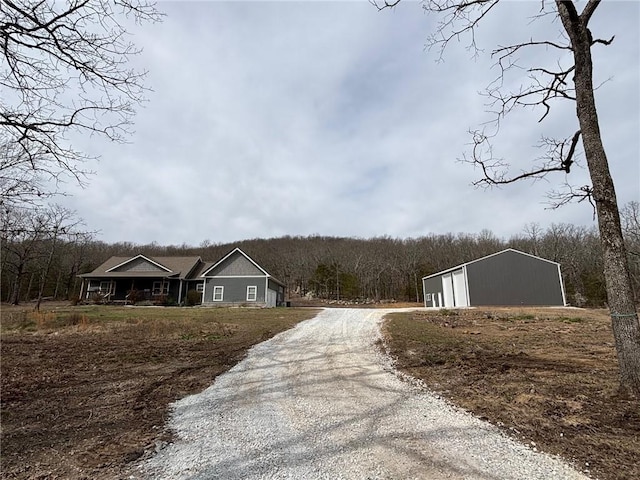 view of street with gravel driveway and a view of trees