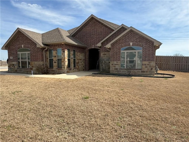 2401 Armstrong Ln, Pea Ridge, AR 72751 - view of front of home featuring fence, a shingled roof, a front lawn, stone siding, and brick siding