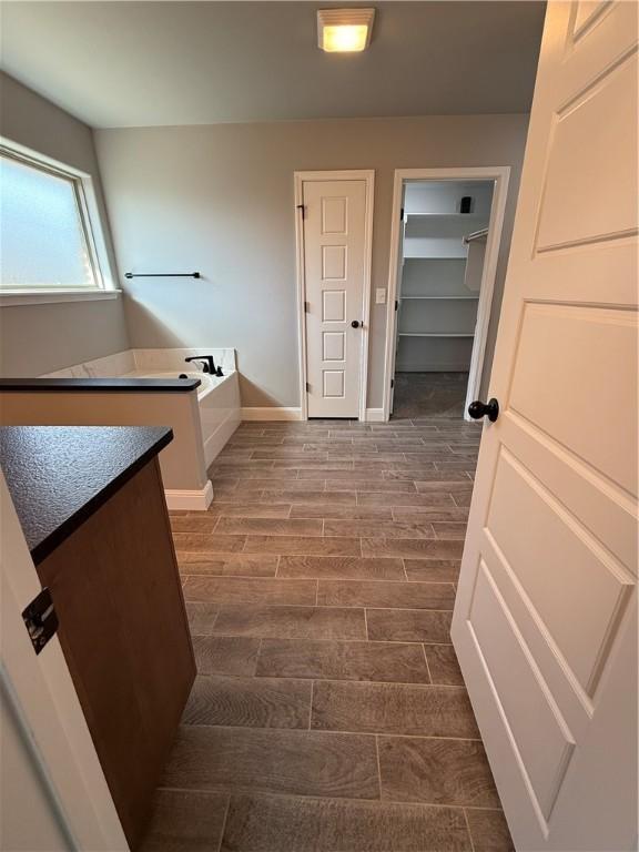 2401 Armstrong Ln, Pea Ridge, AR 72751 - bathroom with a garden tub, baseboards, and wood tiled floor