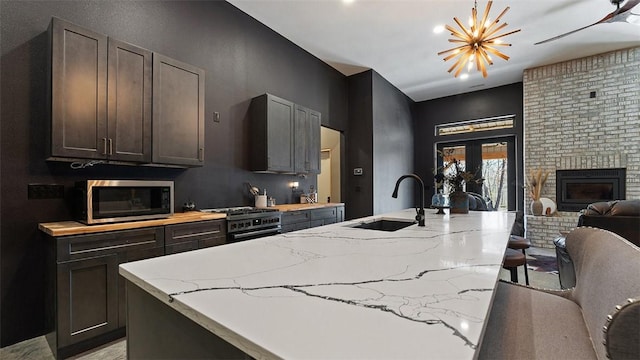 122 SW Gailey Hollow Rd, Siloam Springs, AR 72761 - kitchen with a sink, stainless steel microwave, gas stove, open floor plan, and light stone countertops