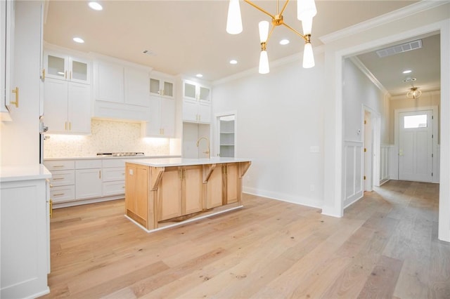 5914 SW Bloomsbury Rd, Bentonville, AR 72713 - kitchen featuring ornamental molding, tasteful backsplash, light countertops, light wood-style flooring, and white cabinetry