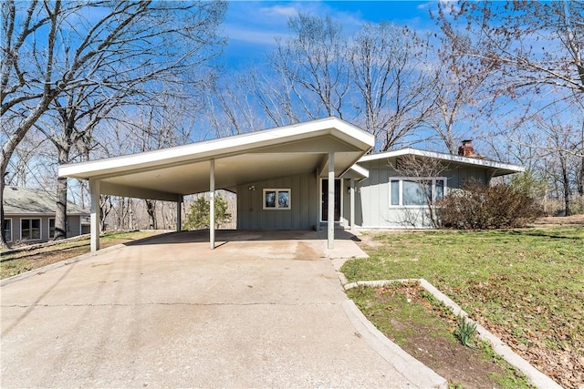 12 Ipswich Dr, Bella Vista, AR 72714 - view of front of property with board and batten siding, a chimney, concrete driveway, a front lawn, and an attached carport