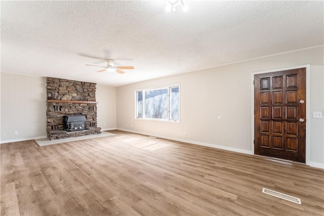 12 Ipswich Dr, Bella Vista, AR 72714 - unfurnished living room featuring a ceiling fan, a textured ceiling, wood finished floors, and a wood stove