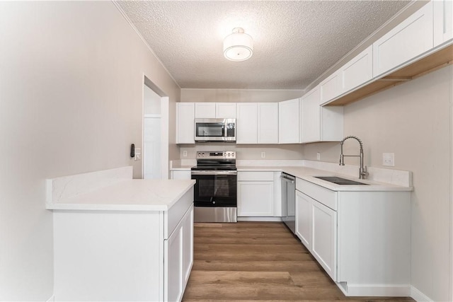 12 Ipswich Dr, Bella Vista, AR 72714 - kitchen with appliances with stainless steel finishes, a textured ceiling, light countertops, light wood finished floors, and white cabinetry