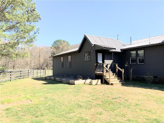 exterior space featuring a yard, fence, and metal roof