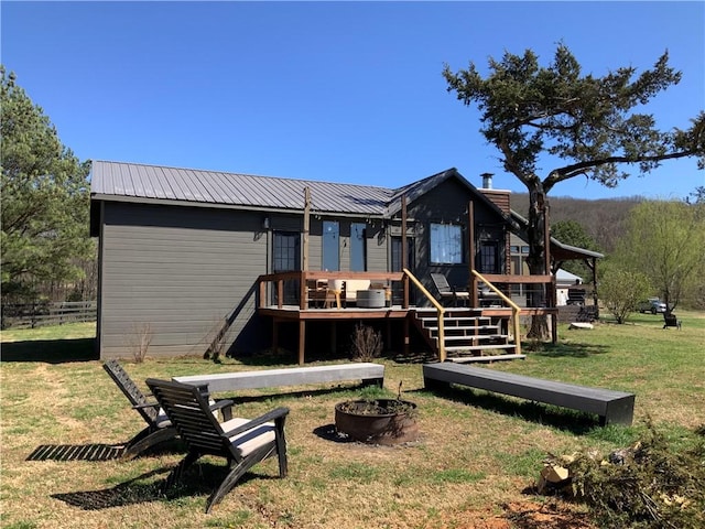rear view of property featuring an outdoor fire pit, a wooden deck, and metal roof