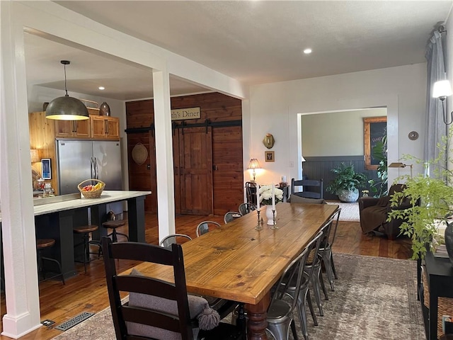 dining space featuring wood finished floors, recessed lighting, visible vents, and a barn door