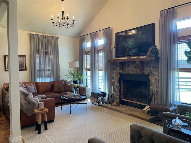 living area with high vaulted ceiling, an inviting chandelier, a fireplace, and plenty of natural light