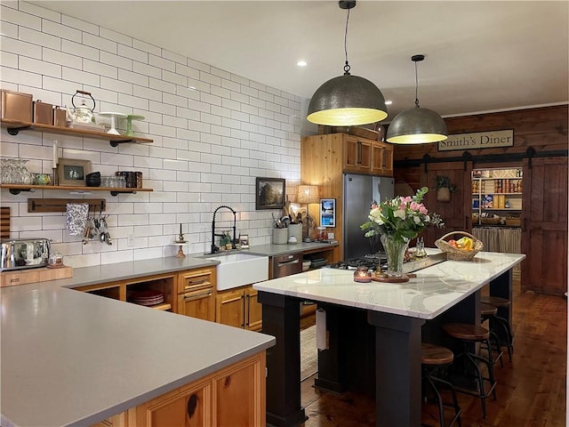 kitchen with a kitchen island, appliances with stainless steel finishes, light countertops, a sink, and decorative backsplash