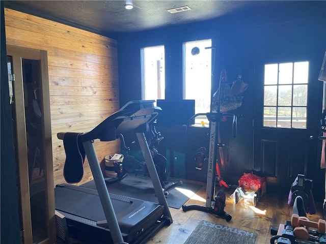 exercise room with a textured ceiling, wood finished floors, and visible vents