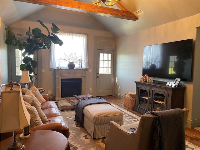 living area featuring light wood-style floors, a fireplace, visible vents, vaulted ceiling, and baseboards